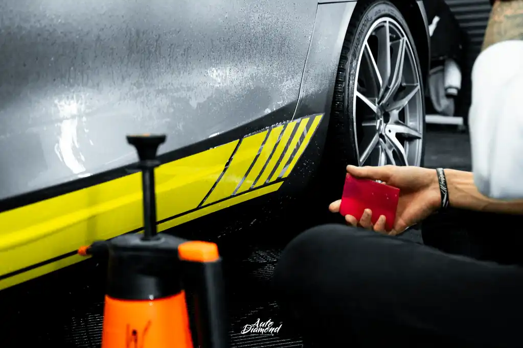 Technik Auto Diamond przy pracy - aplikacja folii na bok samochodu