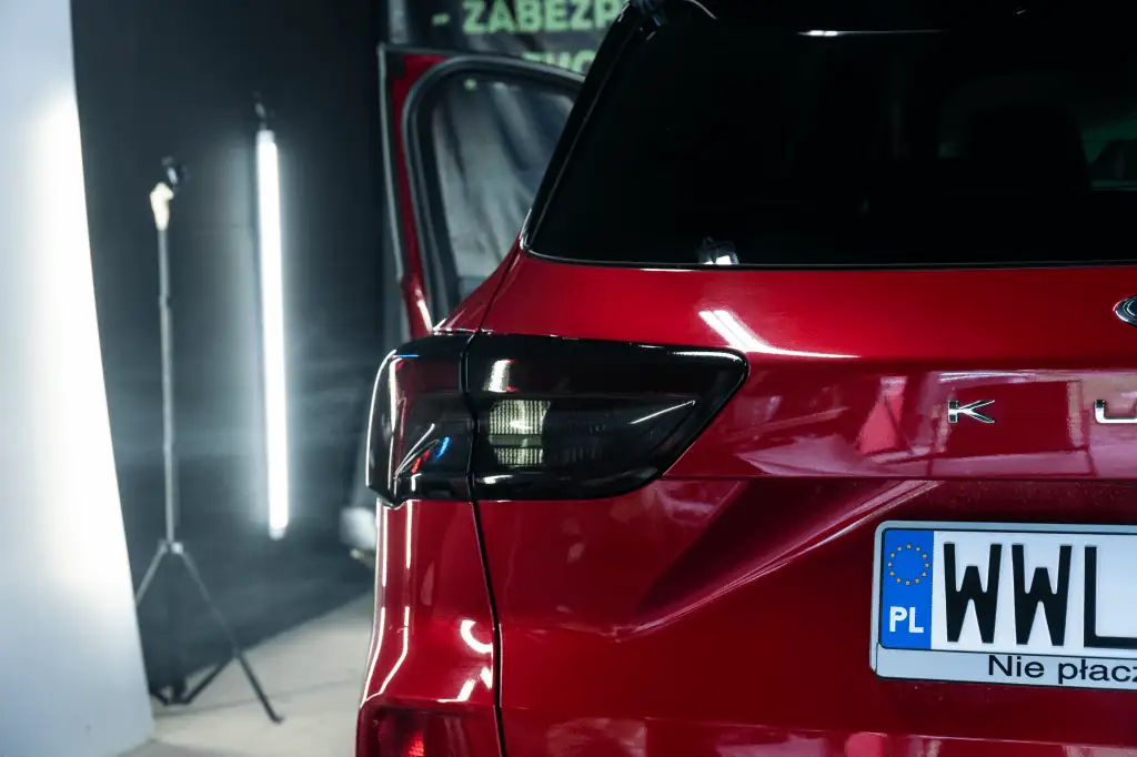 Czerwone auto - zbliżenie na lampę tylną podczas przyciemniania folią smoke