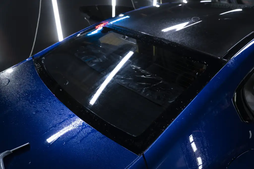 Tylna szyba niebieskiego samochodu podczas nakładania folii przyciemniającej - Auto Diamond