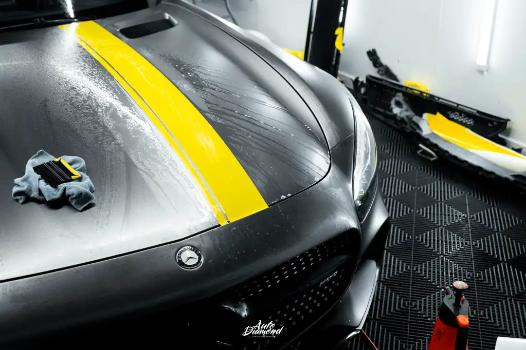 Zbliżenie na maskę Mercedes AMG-GT z żółtymi pasami podczas oklejania - Auto Diamond